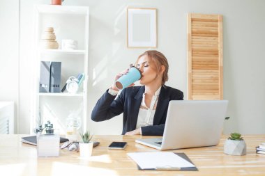 Sakin bir kadın kahve ile ofiste dinleniyor.