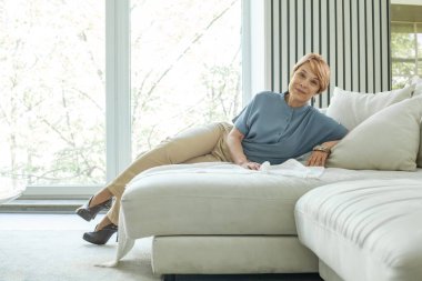 Mutlu olgun kadın, pencerenin kenarında dinleniyor.