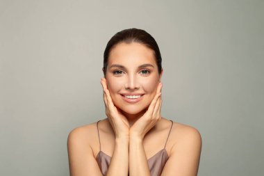 Yanaklarını tutan mutlu, güzel bir kadın. Temiz ciltli güzel bir spa modeli. Kozmetoloji, Güzellik ve Spa