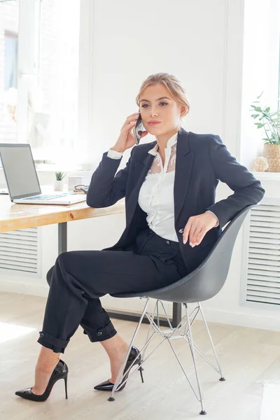 スマートビジネスの女性は笑顔とオフィスで携帯電話で話している — ストック写真