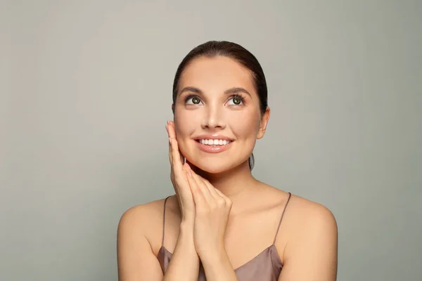 Smiling Young Woman Touching Her Cheek Smiling Looking Grey Background — ストック写真