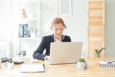 Portrait of business woman in protective face shield using laptop in office
