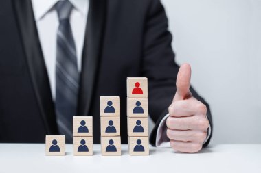 Leadership and success in business concept. Hand holding thumb up near wood blocks with people icon 