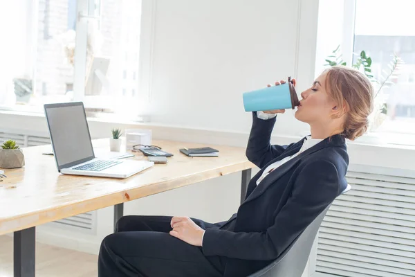 Business lady drinking coffee in office