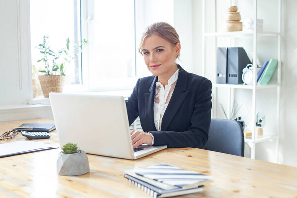 Beautiful business woman sit indoors in office using laptop computer