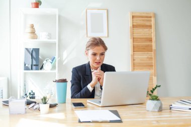 Young businesswoman using laptop and surprised 