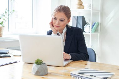 Smiling professional businesswoman working on laptop at office