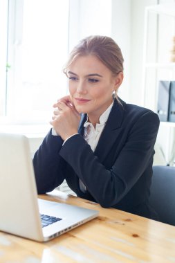 Smiling businesswoman sitting at her desk working on laptop