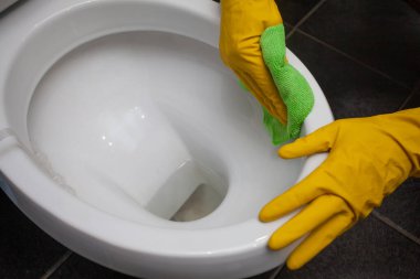 Man cleaning toilet bowl in bathroom