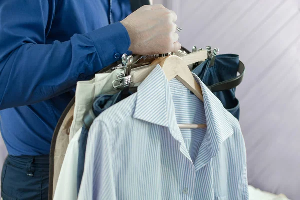 Male fashion, sale, shopping and style concept. Business man in blue shirt choosing wear in mall or clothing store