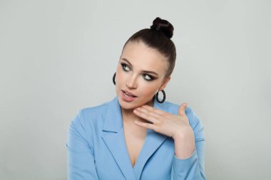 Studio portrait of a beautiful young woman with makeup and dark brown hair, bun hairstyle