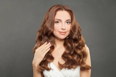 Brunette model with long and shiny wavy hair. Beautiful woman with curly hairstyle.