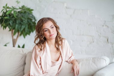 Curly haired blonde woman relaxing on the couch at home.