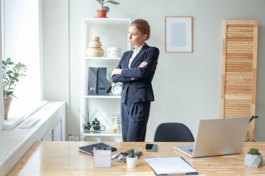 Portrait of thinking business woman in the office. Crossed arms