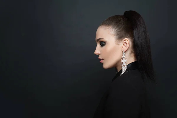 Portrait of fashionable stylish woman in earring. Beautiful female profile  on black banner background with copy space