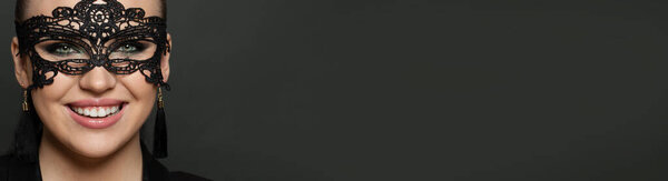 Красивая женщина лицо в карнавальной маске крупным планом. Счастливая женщина в карнавальной маске на темном фоне баннера