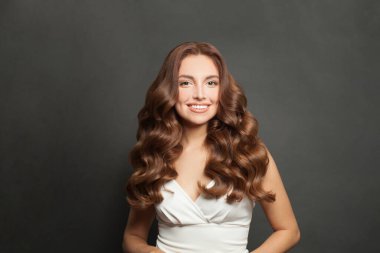 Brunette model with long and shiny wavy hair . Beautiful lady with curly hairstyle .