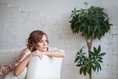 Relaxed smiling woman sitting on sofa at home