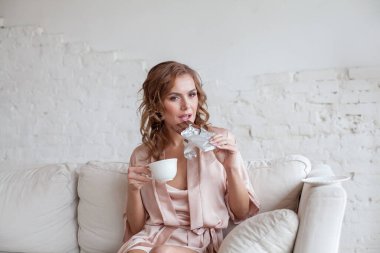 Attractive woman biting a chocolate bar and drinking coffee