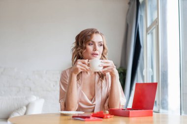 Delighted woman with coffee and chocolate at home in the morning