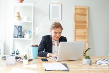 Happy positive businesswoman sitting on chair at office desk
