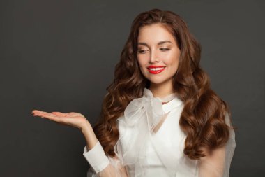 Happy woman holding open hand and smiling on black background