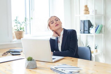 Overworked stressed businesswoman suffering from headache and thinking how to end work