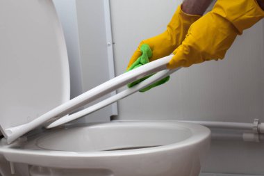 Disinfect, sanitize, hygiene care concept. Man cleaning toilet seat lid 