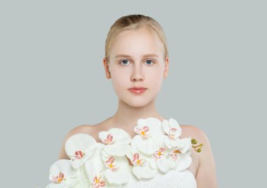 Mükemmel beyaz orkide çiçekleri olan tatlı bir genç kız. Beyaz arkaplan portresindeki sarışın genç kız.