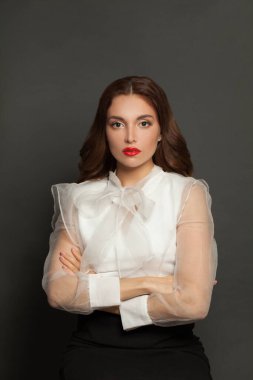 Perfect serious woman with crossed hands standing on gray background
