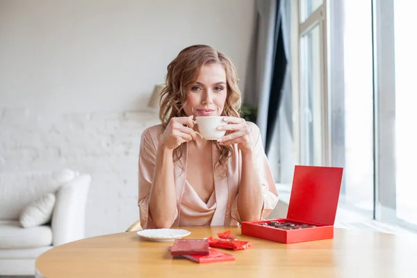 Happy Young Woman Eating Chocolate Candies Drinking Coffee — ストック写真