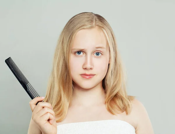 Cute sad teen girl showing comb with hair. Hair loss concept