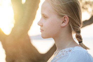 Pretty beautiful young blonde girl on summer park background