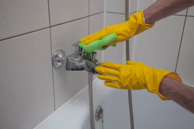 Hands washes the faucet with cloth close up