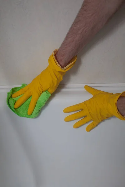 Hygiene and cleanliness concept. Hands in gloves cleaning white wall