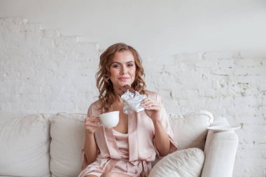 Happy smiling woman with coffee and cocoa chocolate bar at home
