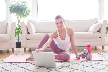 Happy active woman using laptop and getting ready for a workout at home