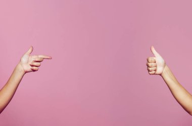 Two female hands pointing and thump up isolated on pink background 