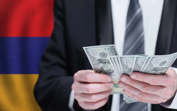 Hands holding dollar money on flag of Armenia