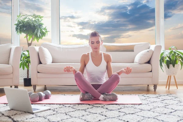 Young adult woman practising yoga at home