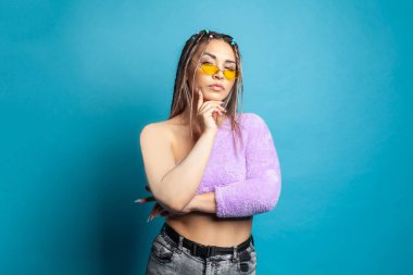 Genç, güzel bir kadın düşünüyor, mavi duvar arkasında şüphe duyuyor.