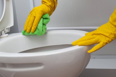 Hands in yellow gloves cleaning a WC