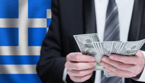 Hands holding dollar money on flag of Greece