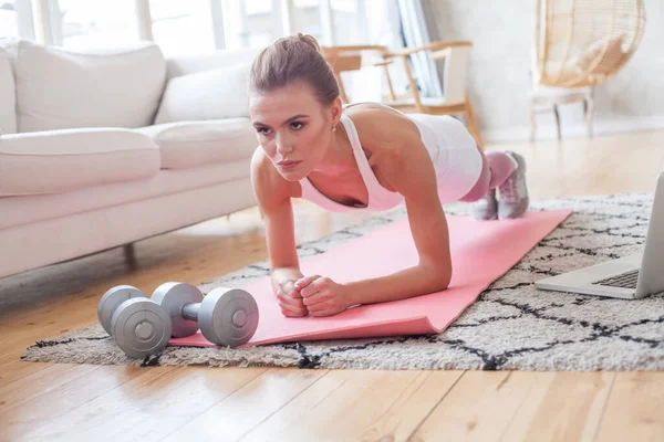 Plank exercise. Sports woman doing exercise plank at home in living room