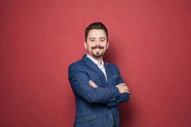 Happy businessmanin blue suit smiling on red background, portrait