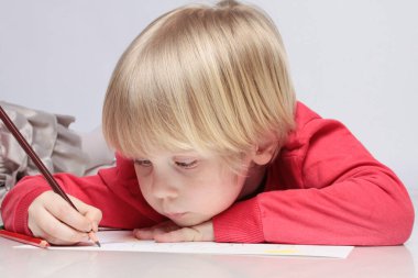 Çocuk pastel boyayla resim çiziyor.