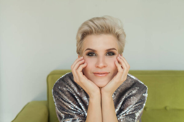 Happy smiling beautiful woman posing with her hand near her face at home