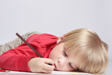 Komik küçük çocuk resim çiziyor.