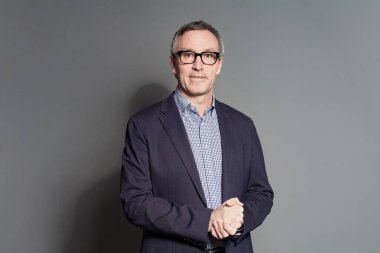 Gri arka planda takım elbiseli kıdemli işadamı.