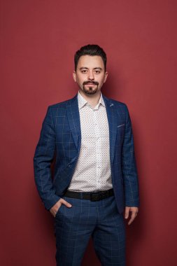 Kırmızı arka planda duran yakışıklı iş adamı.